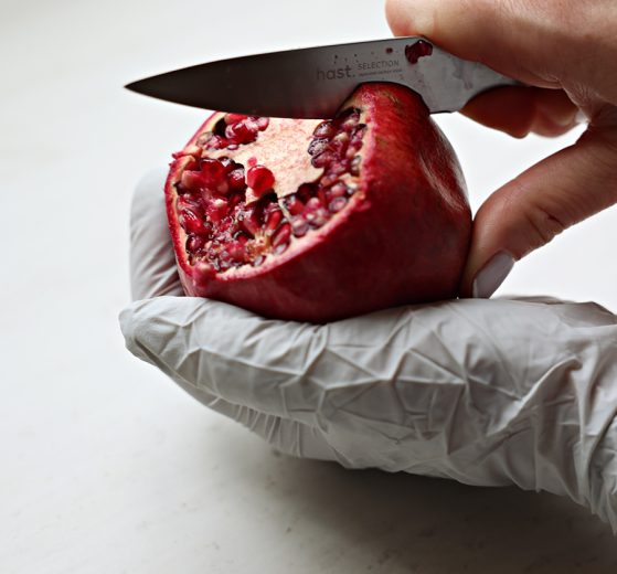 using hast utility knife to score a pomegranate in hand
