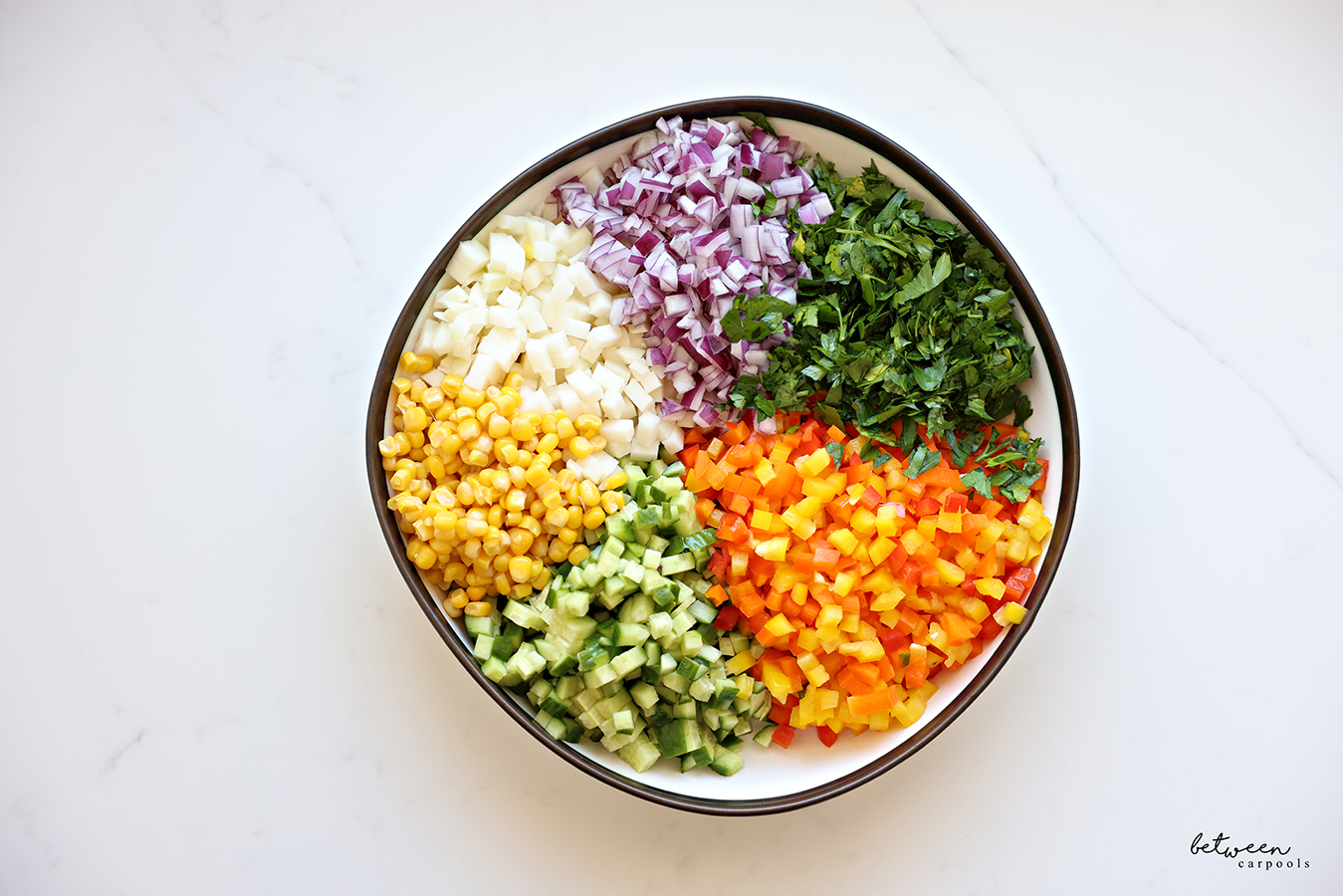 Finely diced fresh vegetables, a pile of each, in a large bowl.