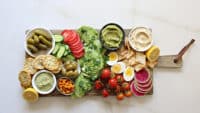 An assembled avocado board, finished with sea salt, and fresh herbs on top of the avocado.