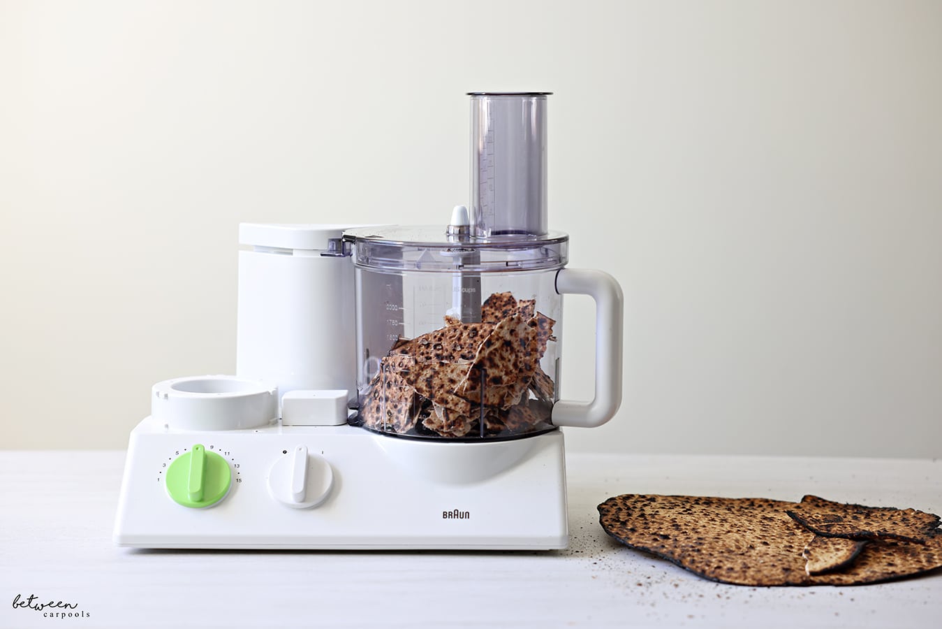 Round shemura matzah in Braun food processor. Some Matzah nearby.