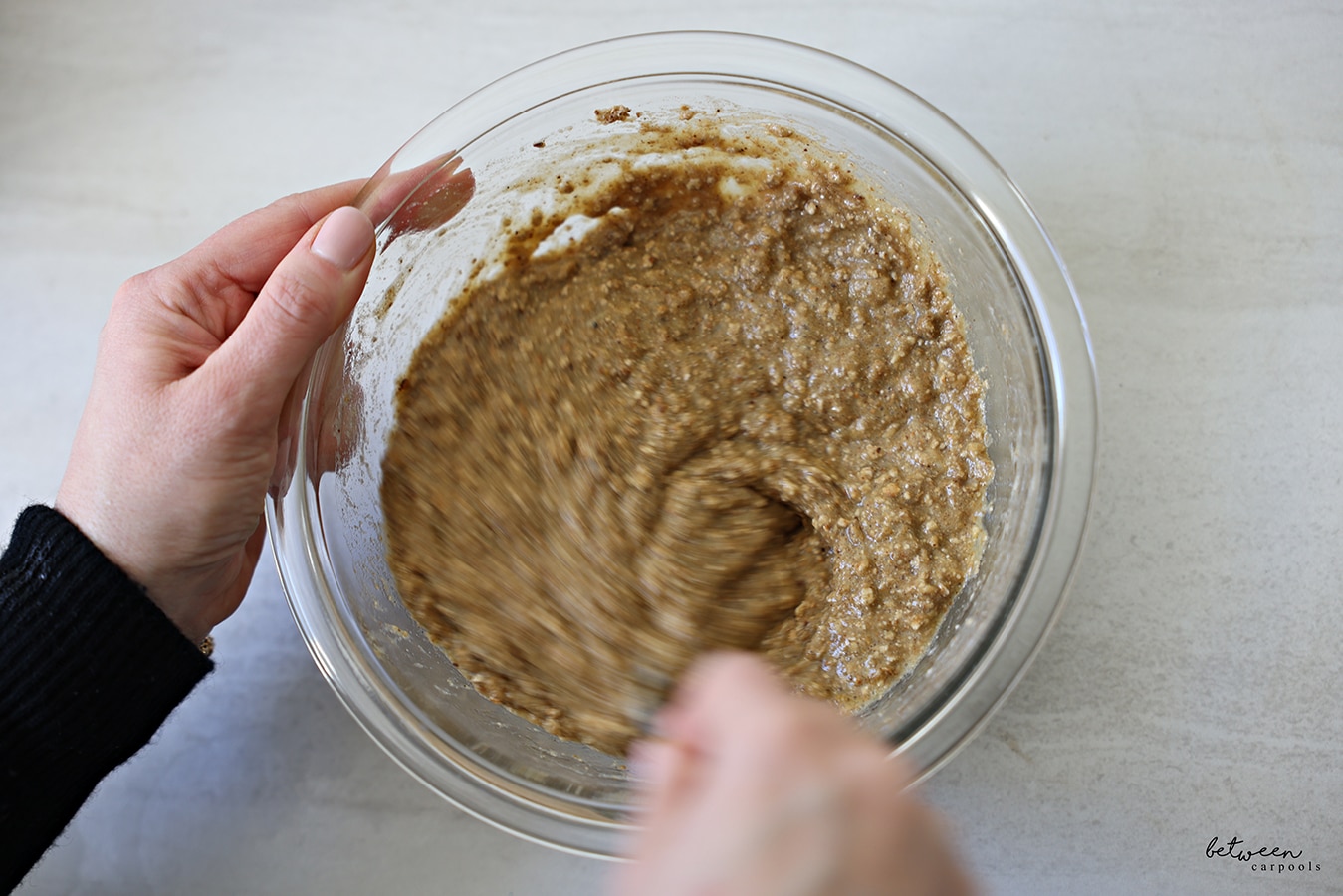Mixing Matzah Ball ingredients in a glass mixing bowl with a fork.