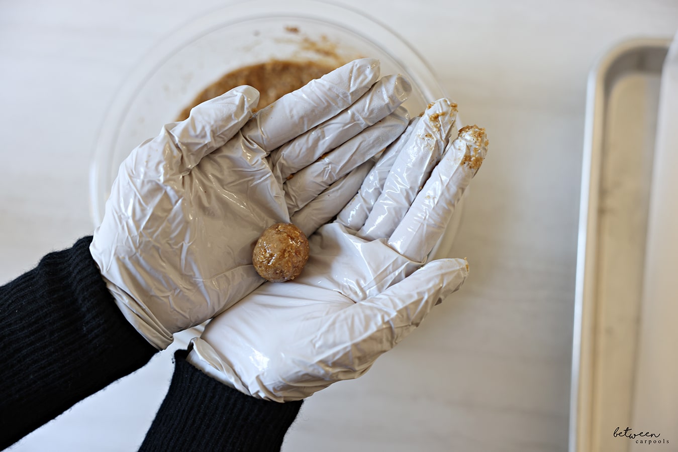 One rolled Matzah ball in gloved and oiled hands.