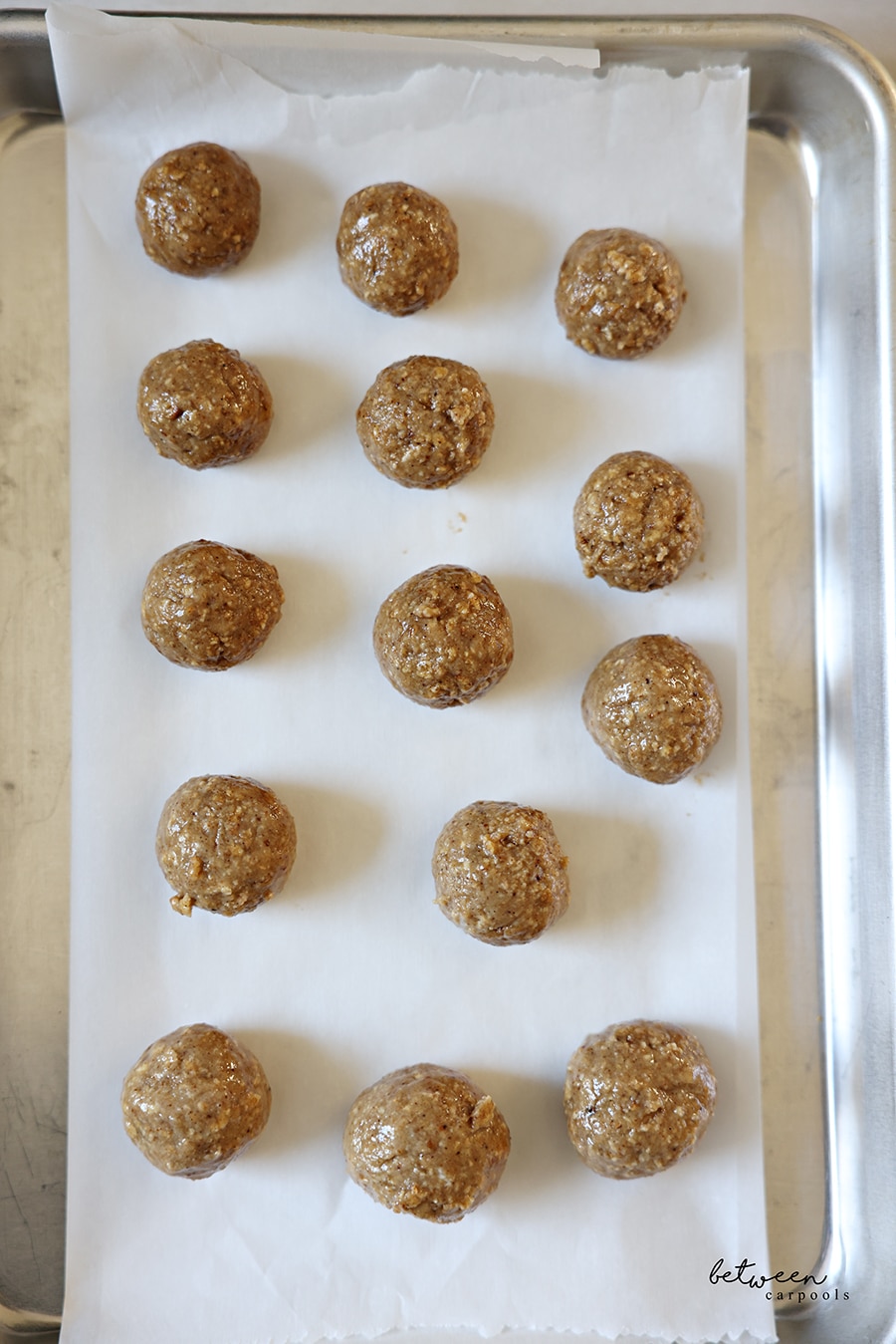 Rolled Matzah balls on a piece of parchment paper on a baking sheet.