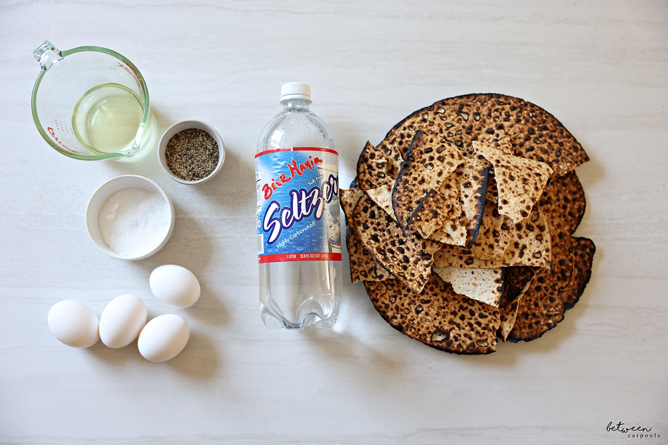 ¼ cup oil in a Pyrex glass measuring cup, salt and pepper, 4 eggs, Be'er Mayim Seltzer, round shemura matzah.