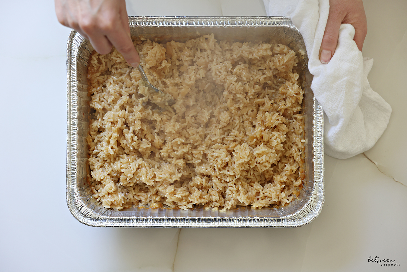 Fluffing steaming hot Baked French Onion Rice with a fork.