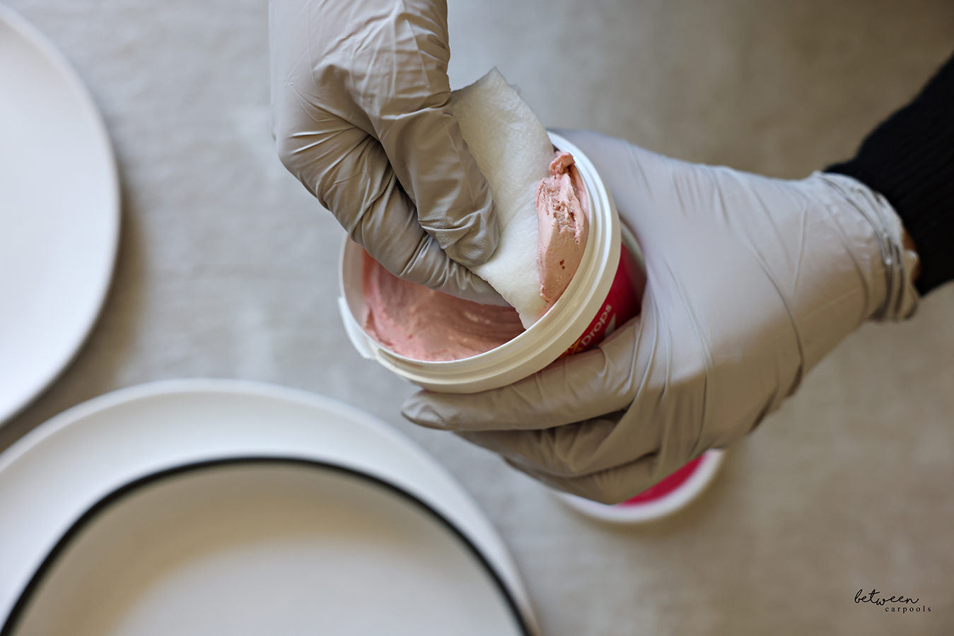 Scooping some The Pink Stuff with gloved hands and a slightly damp paper towel.