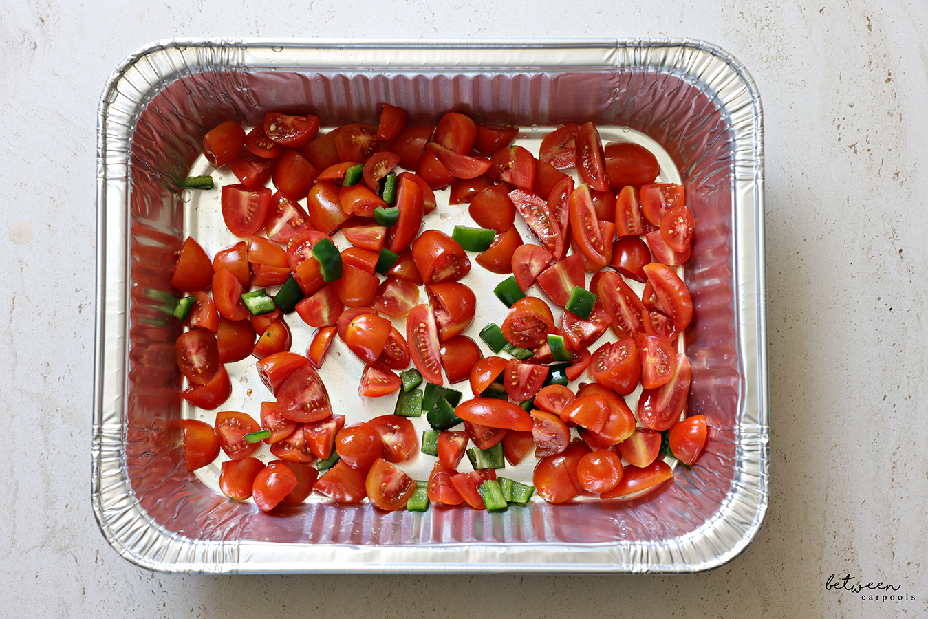 3 cups quartered grape tomatoes and 1 jalapeño, diced, in a 9 x 13 disposable baking pan.