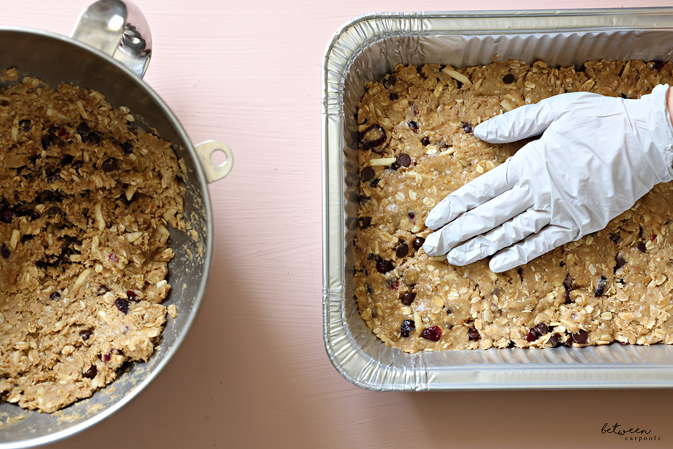 Lactation cookies dough pressed into a 9 x 13-inch baking pan. More cookie dough in the bowl of an electric mixer nearby.