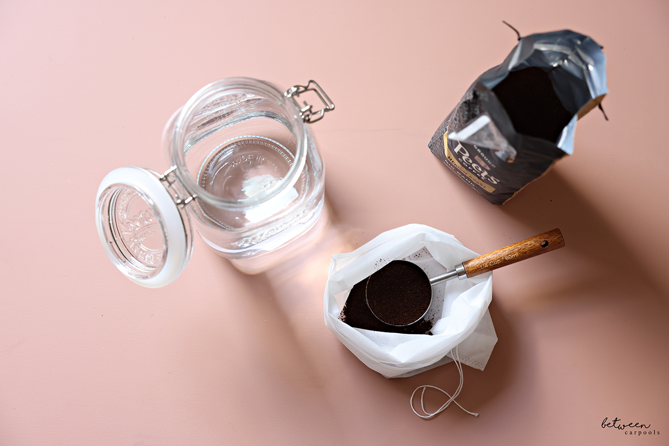 A wide-mouth glass jar, a cold brew bag with coffee grounds and a 1/4 cup measuring spoon, and an open bag of Peet's Big Bang Medium Roast Ground Coffee.