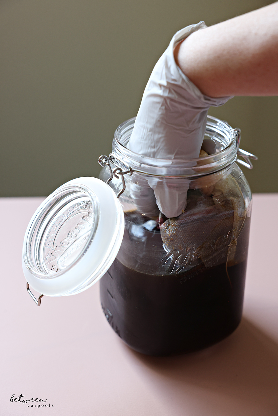 Removing coffee grounds from a wide-mouth glass jar with cold brew.
