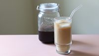 Homemade cold brew in a wide-mouth glass jar and a glass with cold brew over ice with milk.