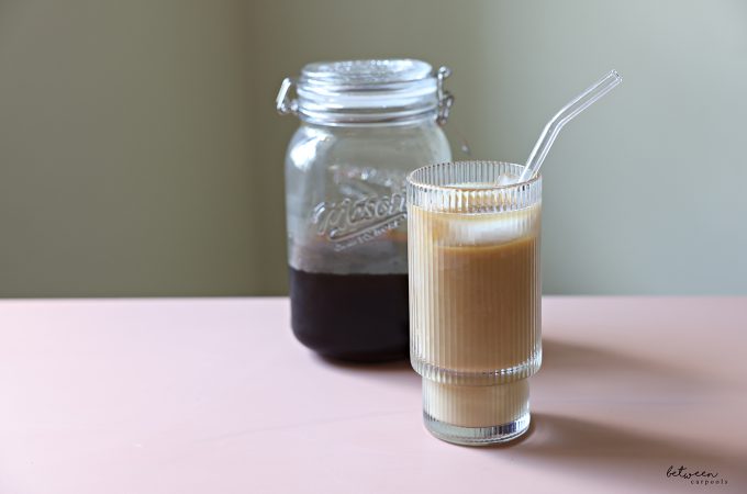 Homemade cold brew in a wide-mouth glass jar and a glass with cold brew over ice with milk.