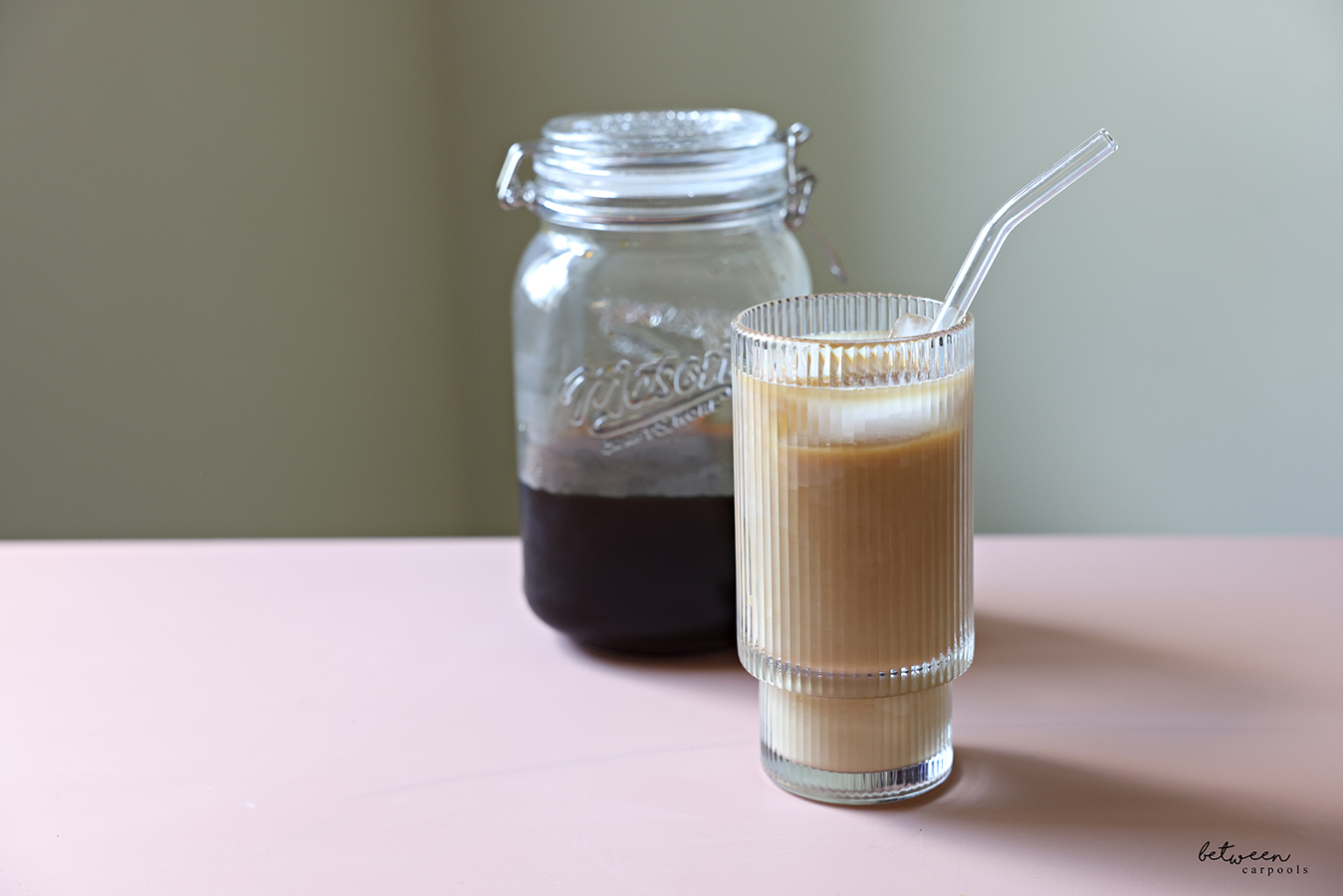 Homemade cold brew in a wide-mouth glass jar and a glass with cold brew over ice with milk.