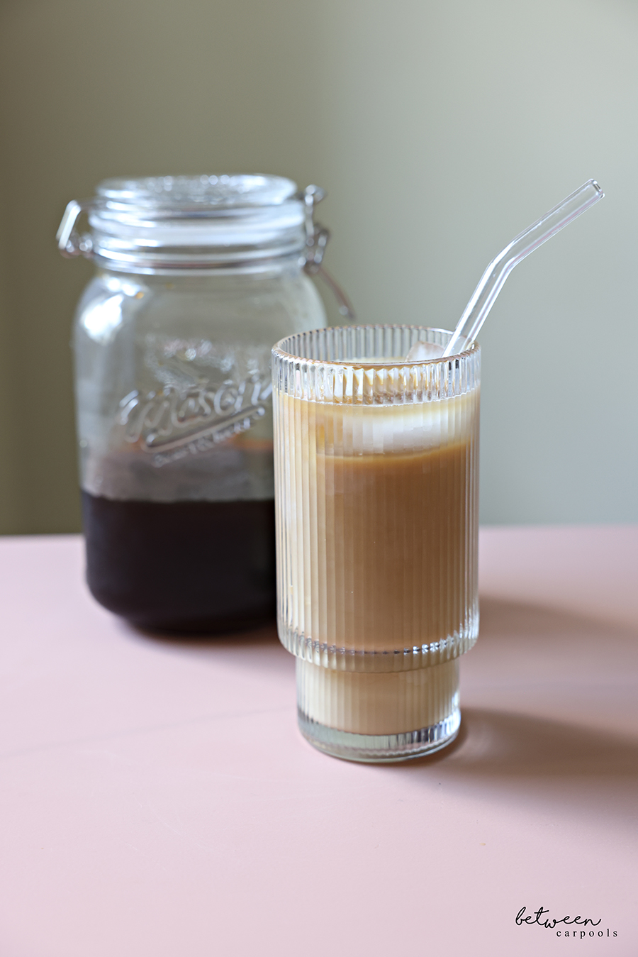 Homemade cold brew in a wide-mouth glass jar and a glass with cold brew over ice with milk.