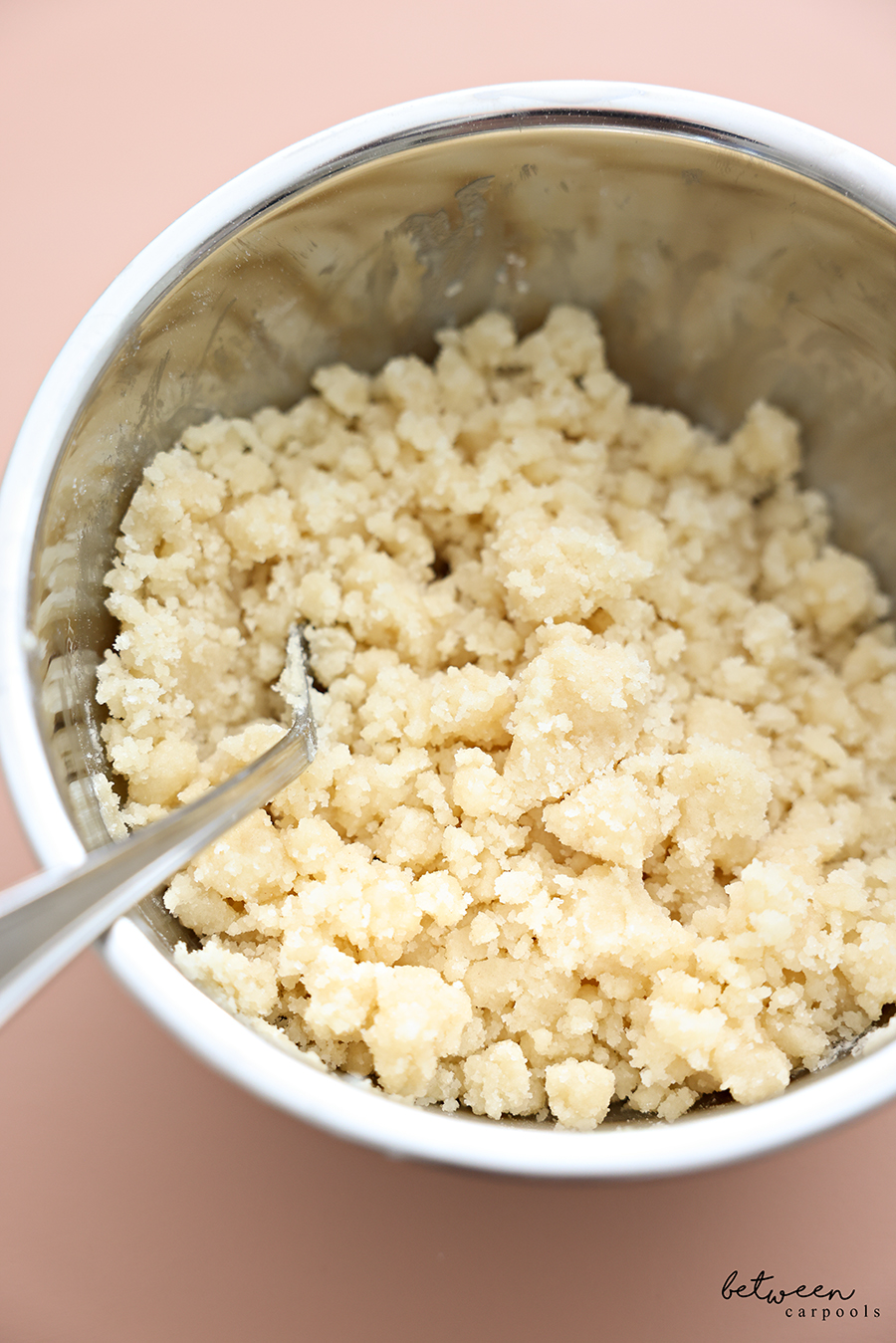 Closeup of streusel crumbs in a metal mixing bowl.
