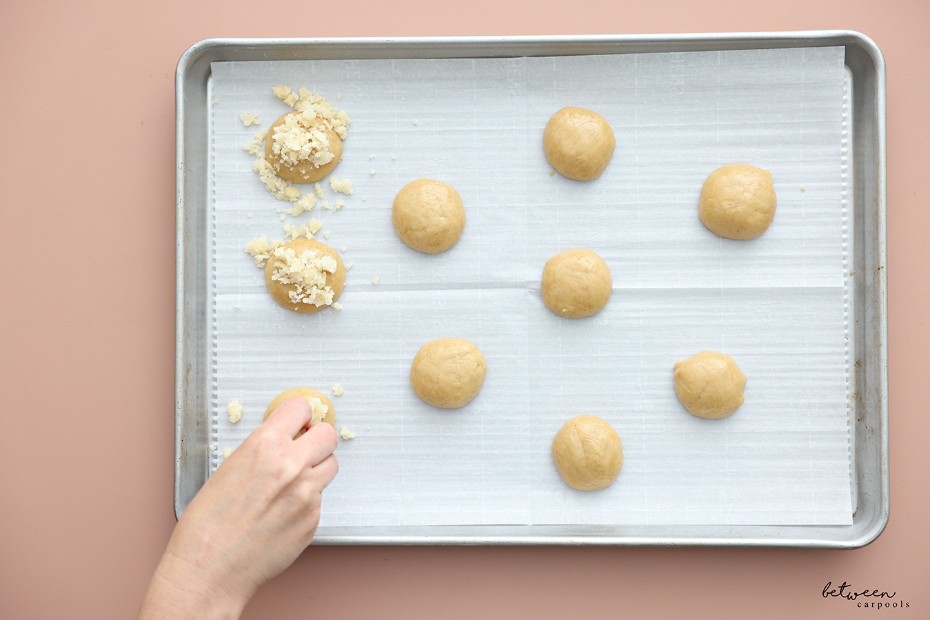Topping balls of honey cookie dough on a parchment lined baking sheet with streusel.