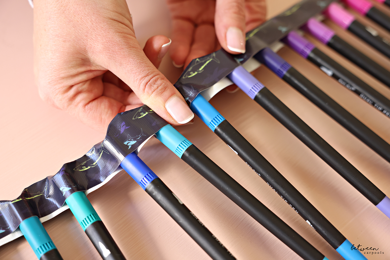Pressing the two sides of duct tape together between marker caps