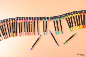 A set of markers, in shade order, its caps held together with duct tape.