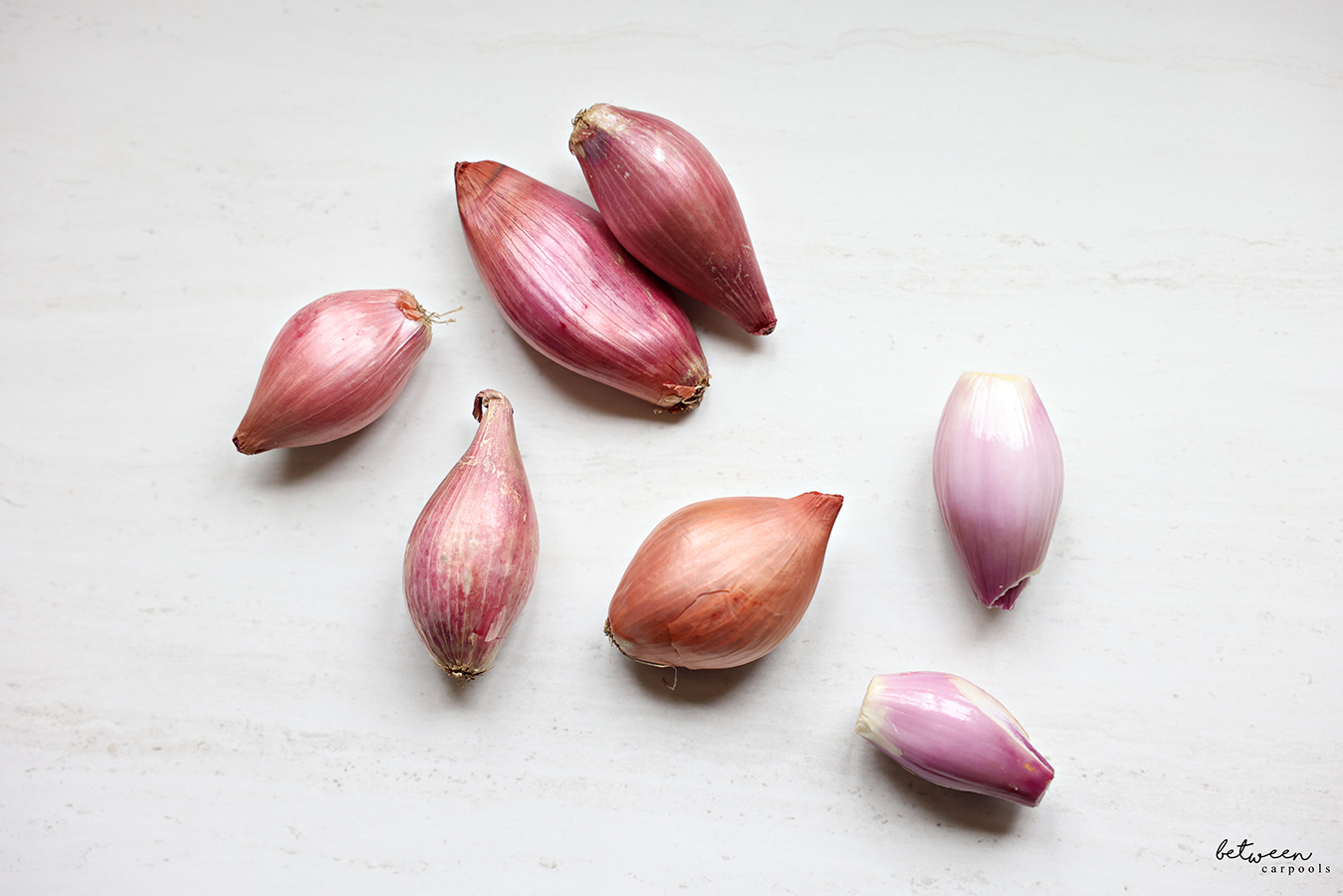 Shallot bulbs + 2 peeled shallots on countertop.