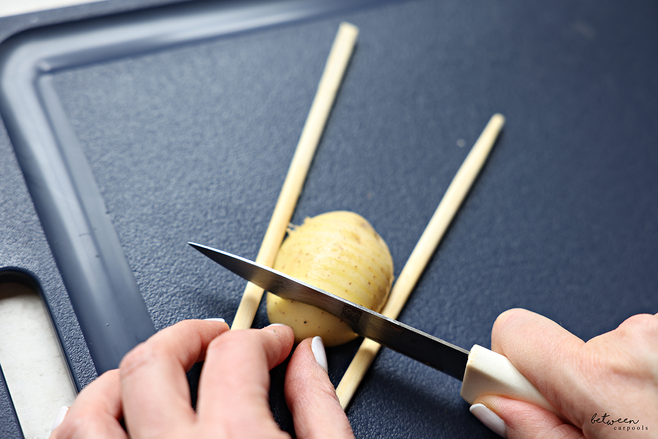 Thinly slicing a half of a baby golden potato between two chopsticks.