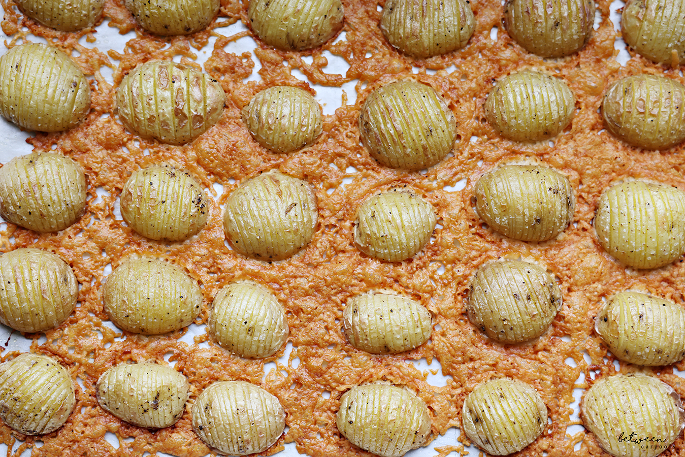 Closeup of Parmesan Hasselback Potatoes on a parchment lined sheet pan.