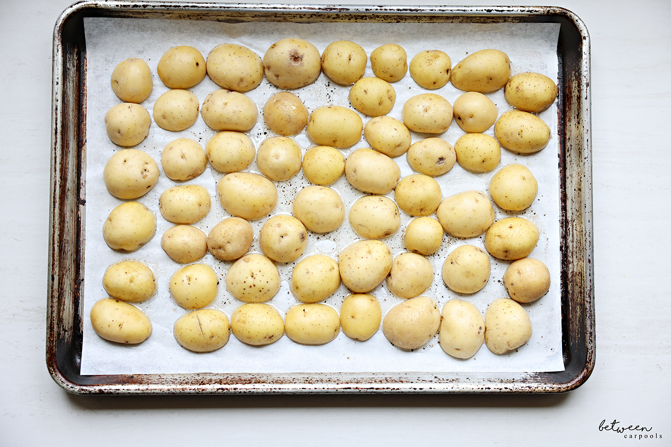 Baby yellow potatoes, halved, cut side down, on a parchment lined baking sheet.