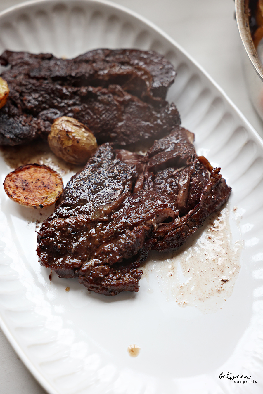 Closeup of boneless flanken and potatoes with red wine on a serving platter.