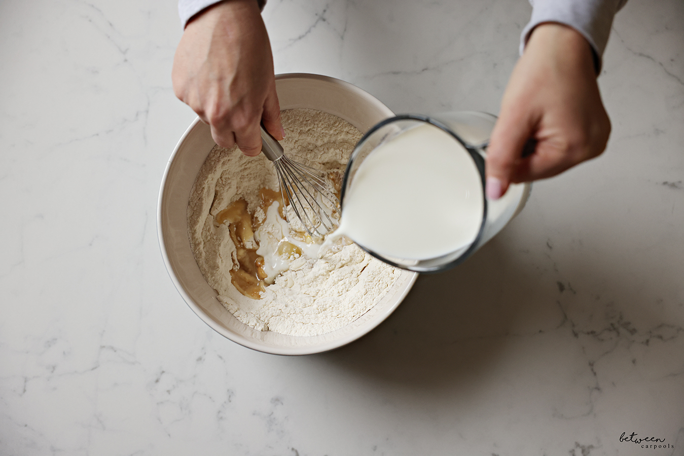 Adding and whisking milk into a bowl with all dry ingredients.