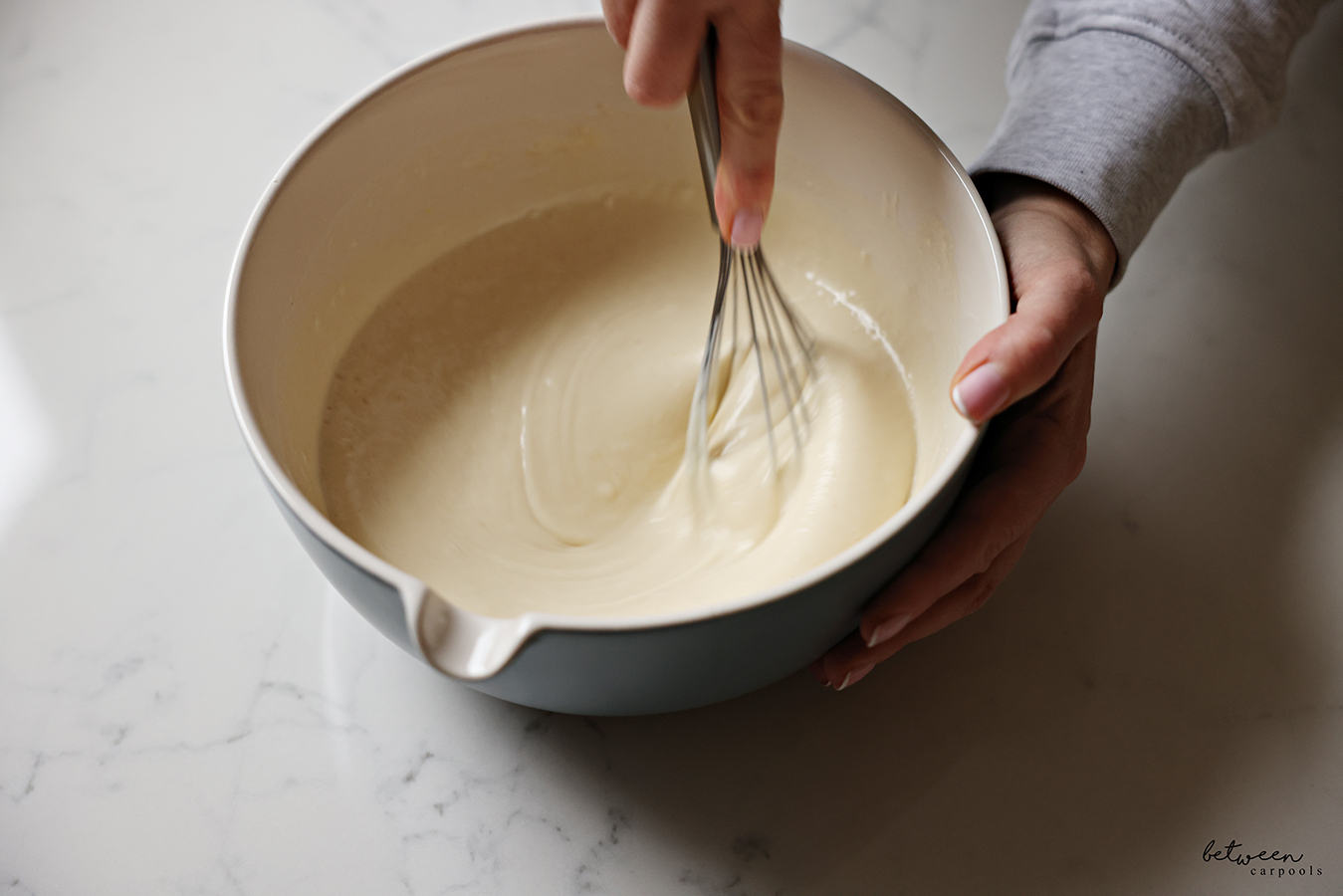 Whisking pancake batter in a large spouted bowl.