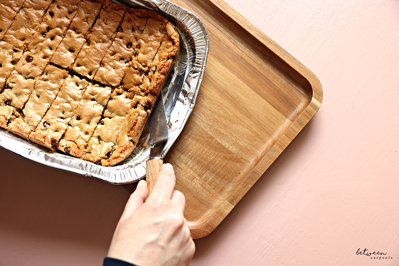 Transferring Between Carpools 9×13 Life: Chocolate Chip Sticks from a tin to bamboo tray with a Spatula.