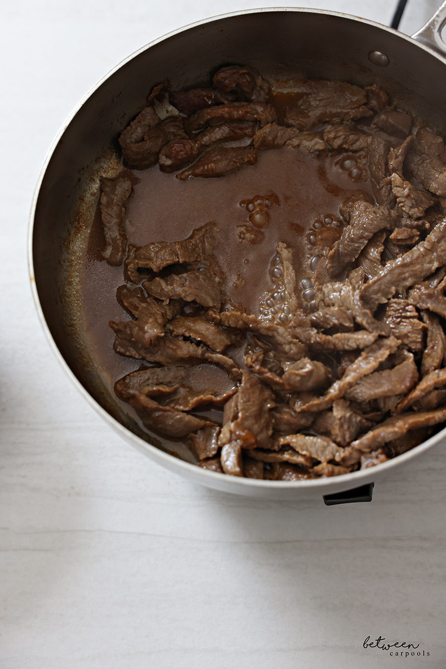 Stir-frying marinated steak in a large pan.