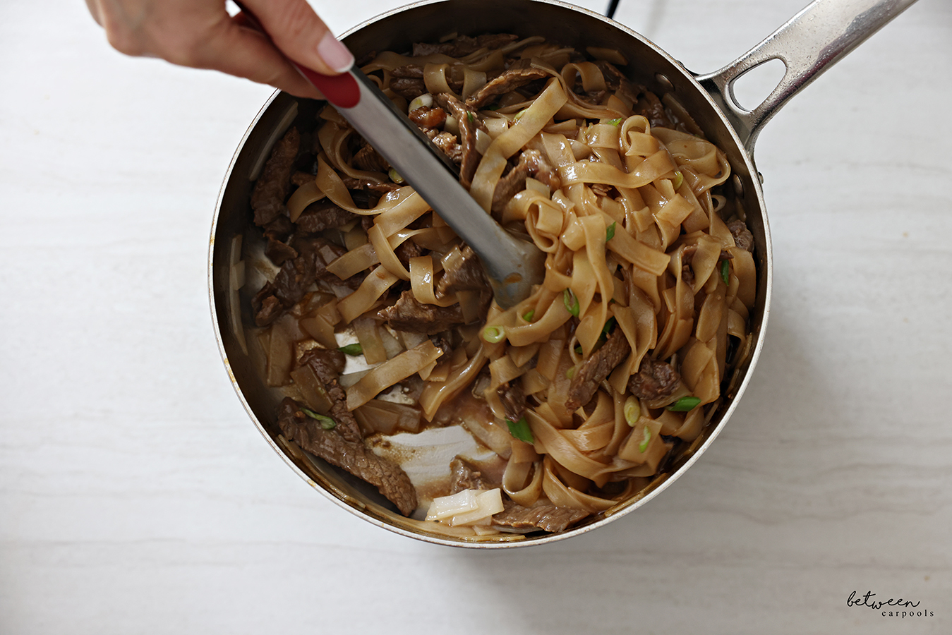 Tossing rice noodles, steak, and stir-fry sauce, together.