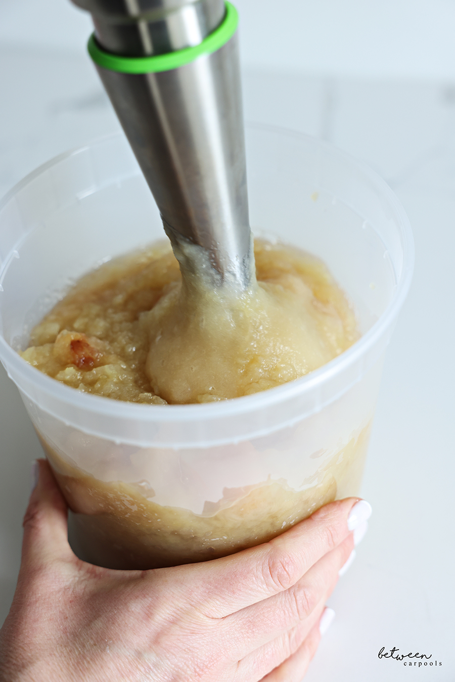 Blending applesauce in a deep deli container.