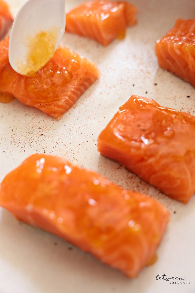 Spooning homemade duck sauce over seasoned salmon.