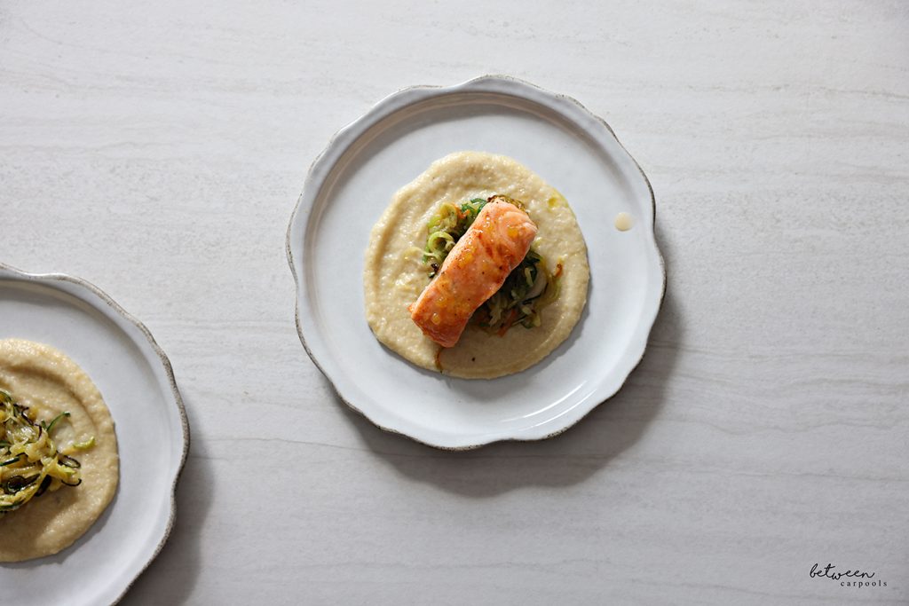 Baked salmon on top of zoodles over eggplant puree on a plate.