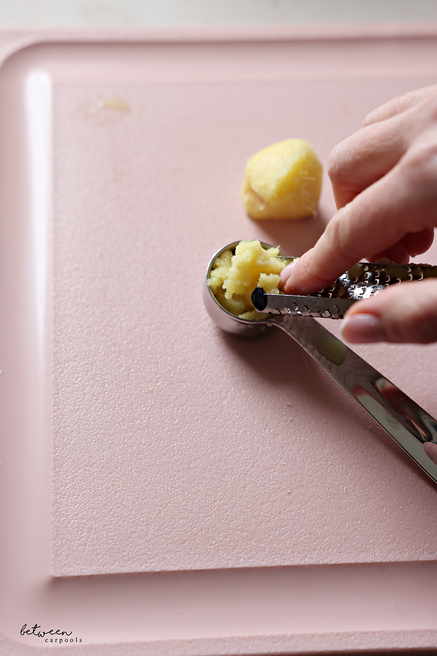 Ginger zest from a microplane into a measuring spoon.