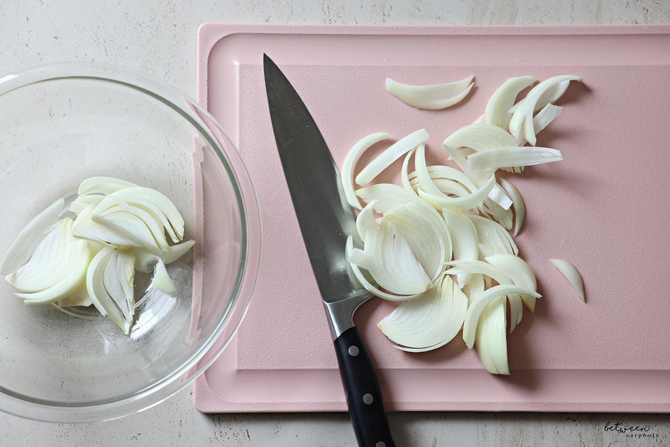 Frenched onions, on a pink cutting board, and in a glass mixing bowl.