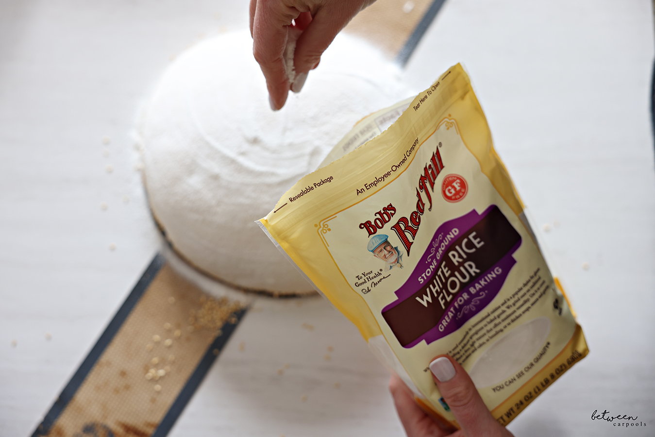 Sprinkling white rice flour on a sourdough loaf on a silpat.
