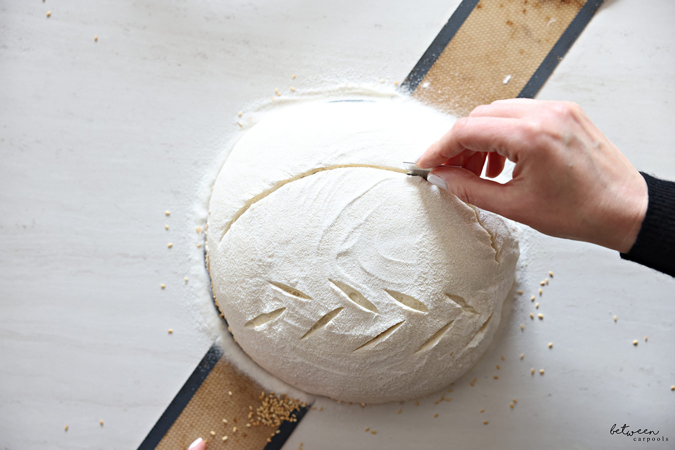 Using a lame to cut an ear into a sourdough loaf.