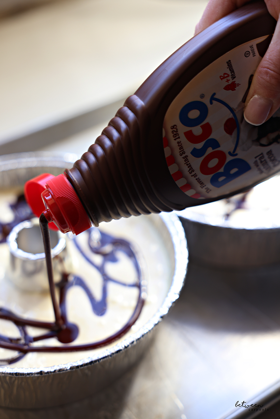 Drizzling chocolate syrup onto marble cake batter in a disposable Bundt pan.