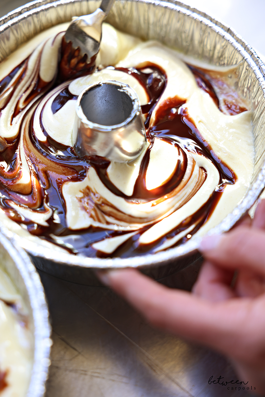 Swirling chocolate syrup through marble cake batter in a disposable Bundt pan.