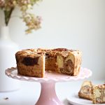 Marble cake on a pink scalloped cake stand. Slices from the cake on a plate nearby.